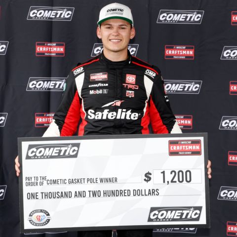 Corey Heim, driver of the No. 11 TRICON Garage Toyota, poses with the pole award check after qualifying for Saturday's NASCAR CRAFTSMAN Truck Series Tyson 250 at North Wilkesboro Speedway.